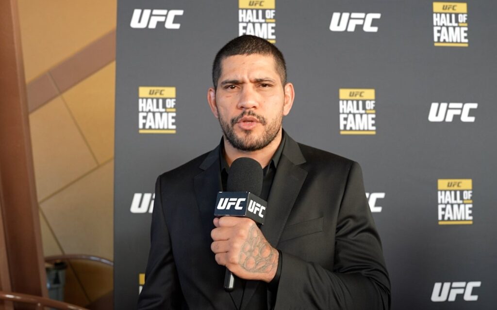 Poatan é rebatido por Dana White e Cormier após acusação 1 Alex Poatan Pereira de terno preto segurando microfone do UFC em entrevista no Hall da Fama