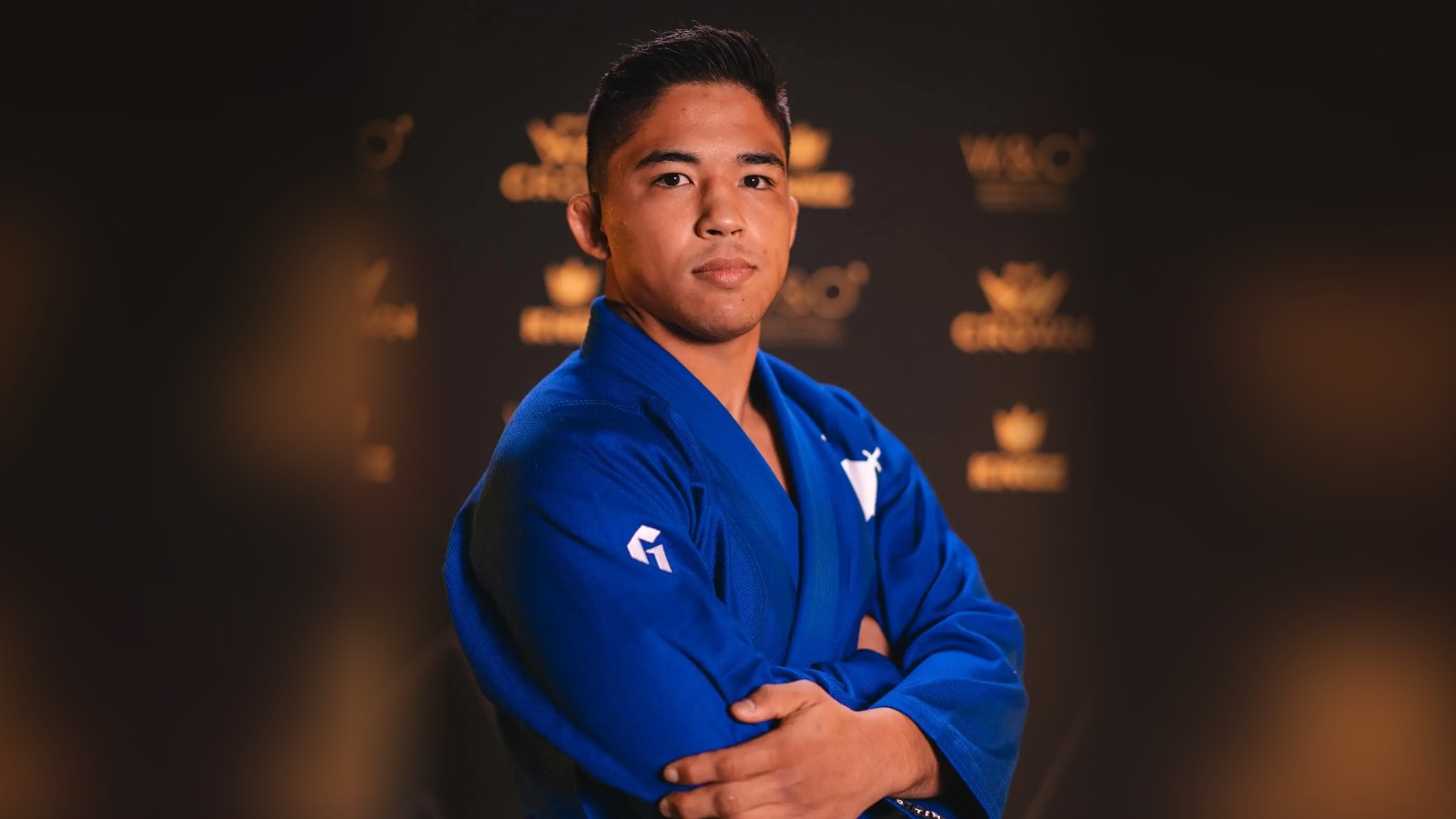 Andy Murasaki leva ouro duplo em Houston antes do Crown 1 Andy Murasaki, de kimono azul e braços cruzados, em retrato da IBJJF no media day do The Crown 2025