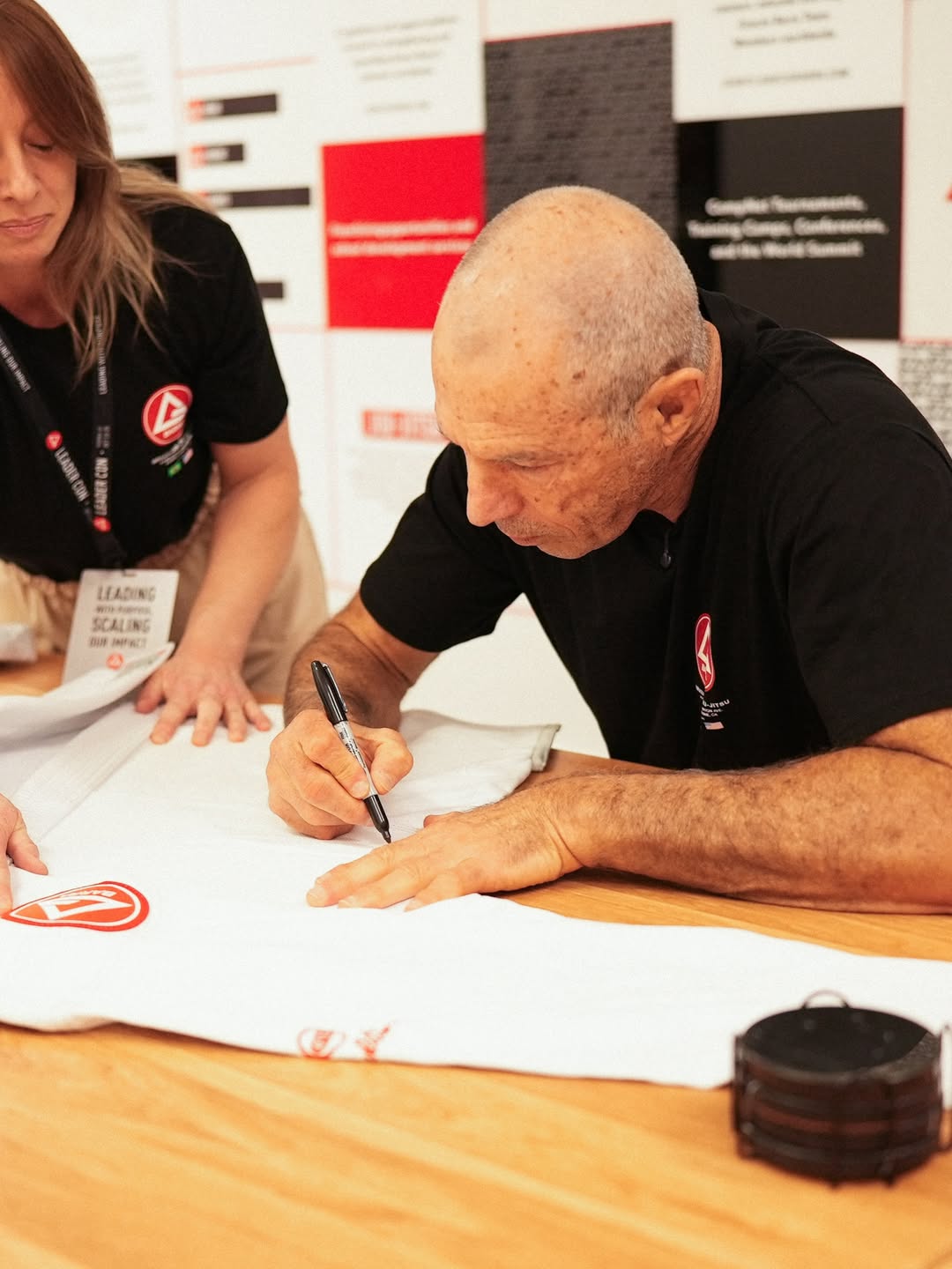 Carlos Gracie Jr. autografa um kimono branco sobre a mesa