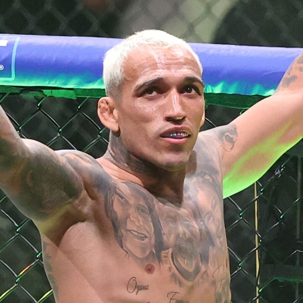 Charles do Bronx, sem camisa e de braços abertos no octógono, comemora a vitória sobre Max Holloway no UFC 326