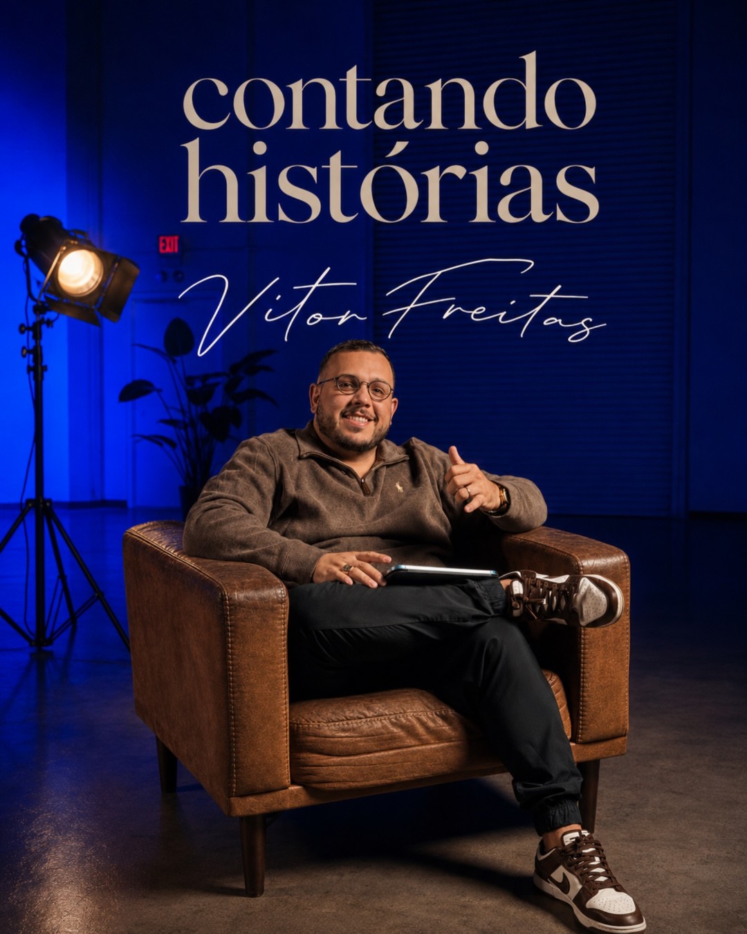 Capa da série Contando Histórias: Vitor Freitas sentado em uma poltrona de couro, em um estúdio com luz azul