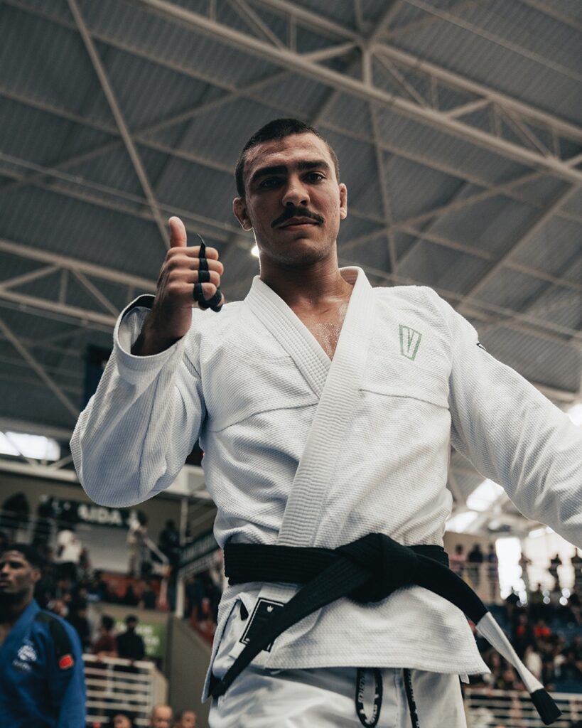 Davi Vetoraci é confirmado no peso-pesado do Crown 2026; Gustavo Batista está fora por lesão 1 Davi Vetoraci, de kimono branco e faixa-preta, faz sinal de positivo em um ginásio