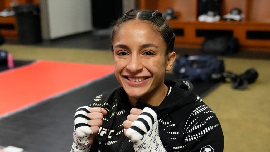 Jaqueline Amorim sorri e mostra as mãos enfaixadas no vestiário do UFC