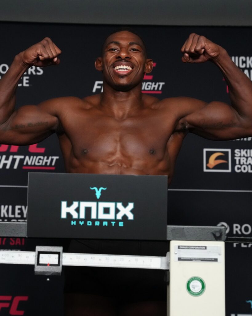Mike Malott provoca Buckley e bate o peso no UFC Edmonton 1 Joaquin Buckley sorri e flexiona os braços na balança da pesagem do UFC Edmonton