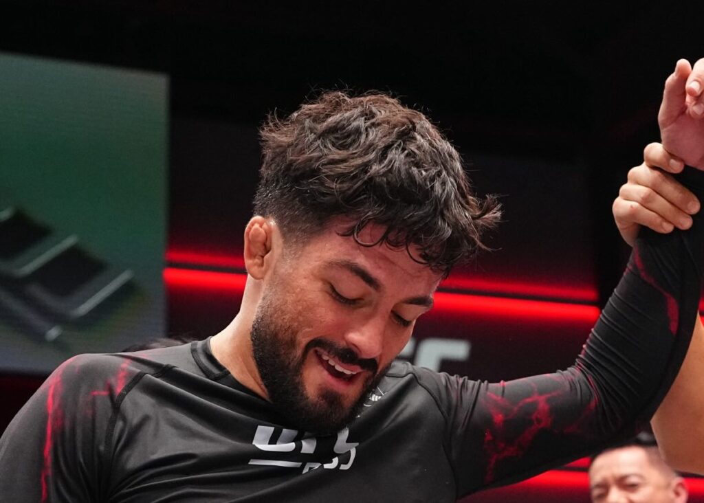 Renato Canuto é o novo campeão peso-leve do UFC BJJ 1 Renato Canuto sorri com o cinturão de campeão do UFC BJJ na cintura e o braço erguido