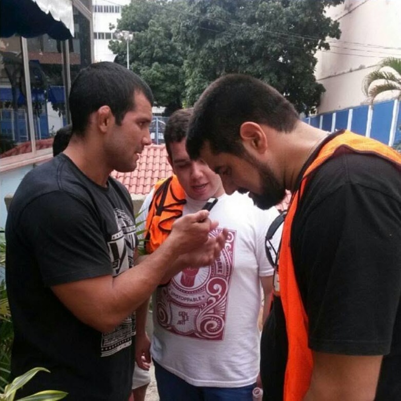 Vitor Freitas, ao centro, olha o celular ao lado de dois homens durante uma cobertura