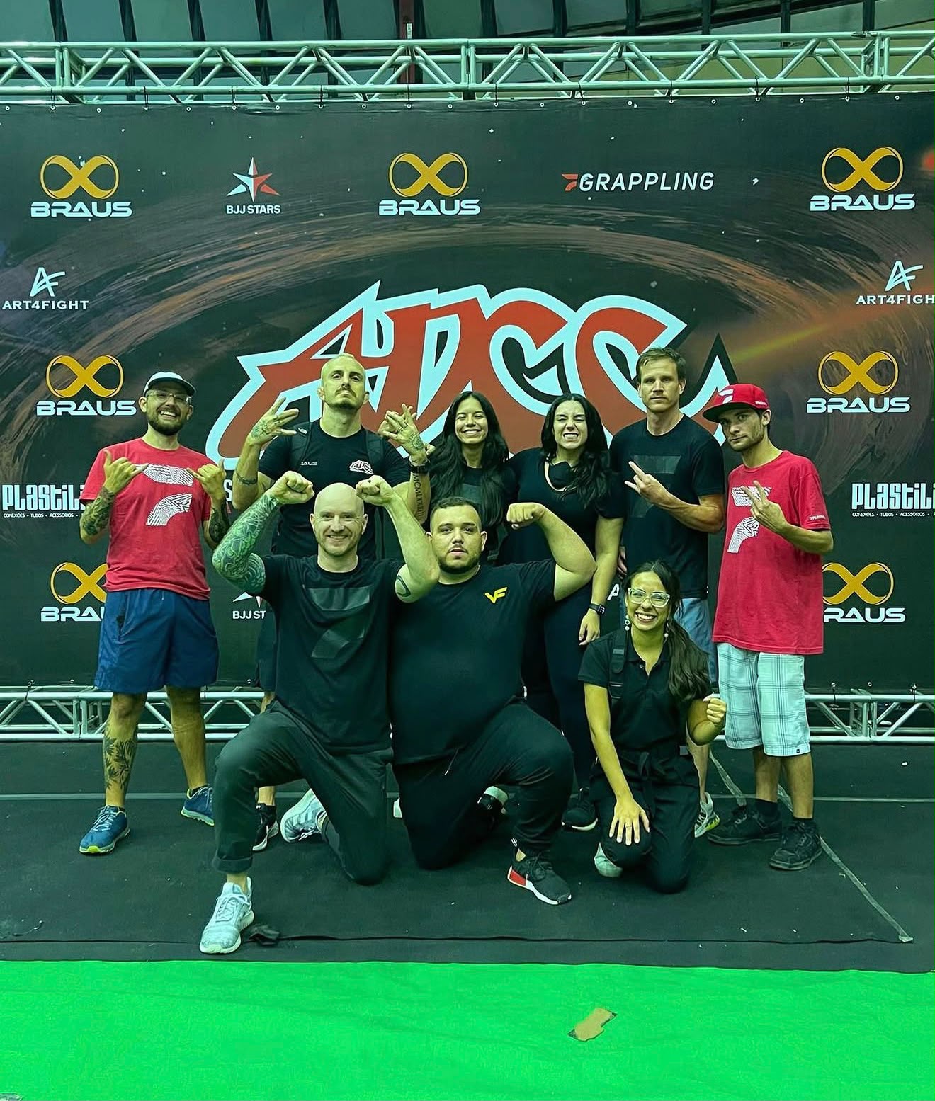Vitor Freitas posa com a equipe da FloGrappling em frente ao painel do ADCC, na seletiva brasileira de 2022