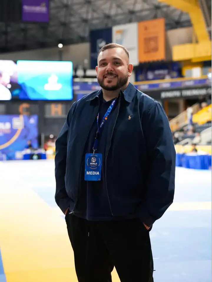 About Us 1 Vitor Freitas wearing a press credential, matside at a Jiu-Jitsu tournament